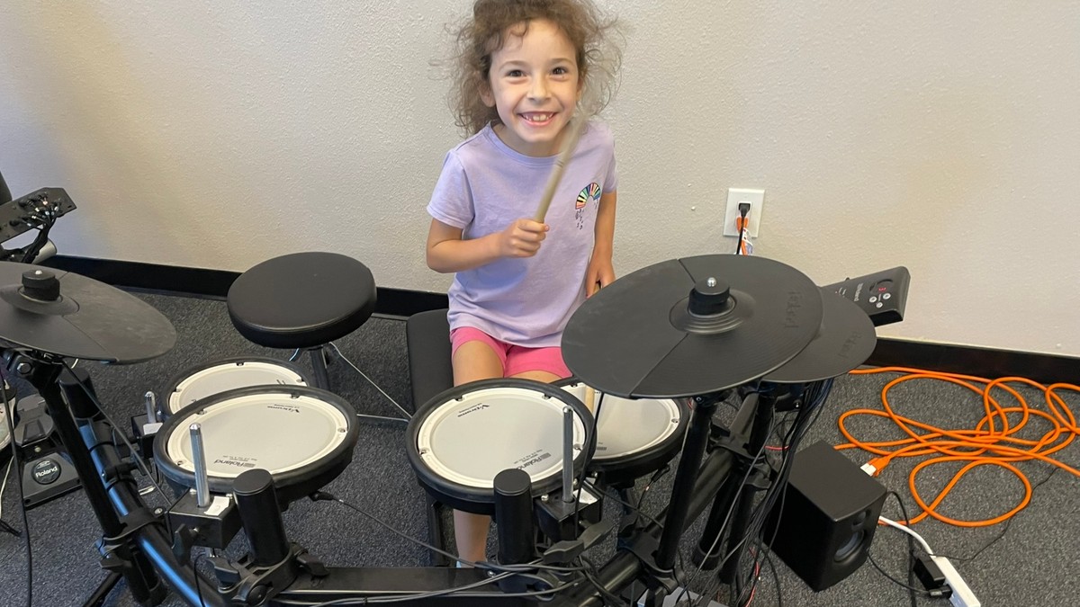 Mini Musicians student smiling while playing electronic drums